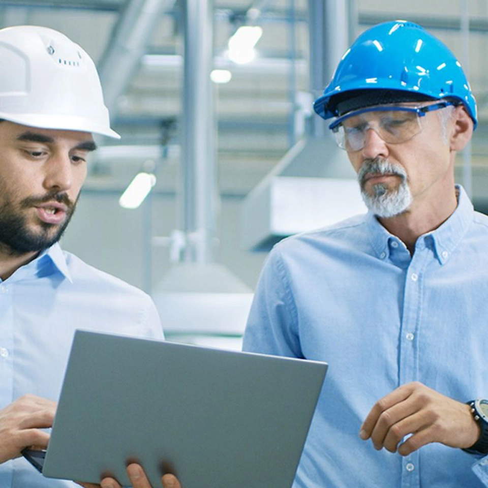 2 men discussing results using a laptop in a manufacturing facility