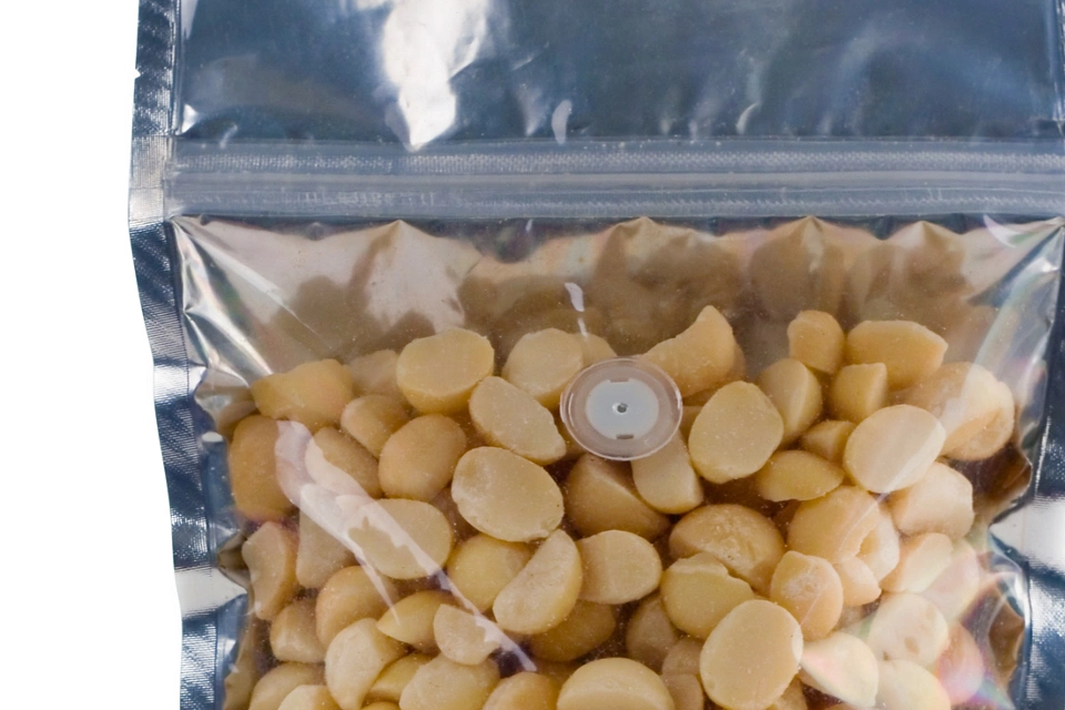 A zip top foil pouch filled with halved macadamis nuts.  Ready for your label design or logo.